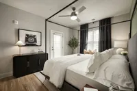 Chic bedroom featuring a stylish canopy bed, elegant decor, and a modern ceiling fan.
