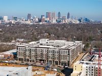 Modern apartment complex with a stunning city skyline backdrop, showcasing urban living with luxury and convenience.