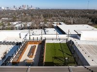 Expansive urban rooftop terrace with sleek seating areas, vibrant greenery, and captivating city views.