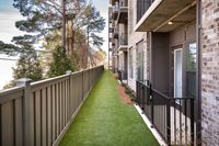 Charming apartment exterior featuring lush green pathway, modern brick design, and private balconies, surrounded by serene trees.