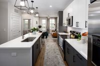 Modern apartment kitchen with sleek countertops, elegant lighting, and cozy living area in the background.