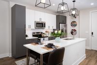 Modern kitchen with sleek white cabinetry, stainless steel appliances, and an elegant island with seating, accented by contemporary pendant lighting.