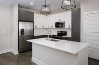 Modern kitchen with sleek stainless steel appliances, elegant black and white cabinetry, and a spacious island with a built-in sink.
