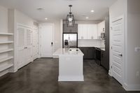 Sleek modern kitchen with elegant white cabinetry, stainless steel appliances, and a chic pendant light enhancing the open-concept space.