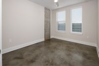 Modern minimalist room with polished concrete floors and bright natural light from two large windows.