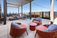 Modern rooftop patio with stylish seating, outdoor dining area, and open sky views, perfect for relaxation and entertaining.