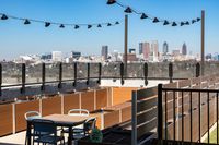 Chic rooftop patio with seating area, modern planters, and breathtaking skyline views under stylish string lights.