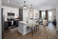 Modern open-plan kitchen and living room with sleek design, featuring elegant lighting, stylish hardwood floors, and a cozy seating area with city views.