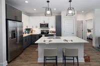Chic modern kitchen with sleek stainless steel appliances, elegant cabinetry, and a stylish island with seating for two. Bright, inviting, and perfect for entertaining.