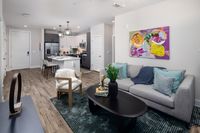 Modern open-concept apartment living room showcasing sleek kitchen island, contemporary furniture, and vibrant artwork.