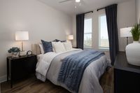 Elegant bedroom with stylish decor, featuring a plush bed with textured pillows, ambient lighting, and large windows with panoramic city views.