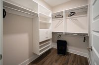 Spacious walk-in closet with modern shelving, hanging rails, and sleek hardwood flooring, perfect for all your storage needs.