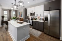 Modern kitchen featuring sleek white and dark cabinetry, stainless steel appliances, and an inviting island with pendant lighting.