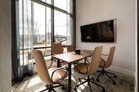 Bright and modern office space with sleek conference table, comfortable chairs, large window, and mounted TV, perfect for productive meetings.
