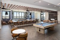 Luxurious open-concept entertainment room featuring a modern kitchen with bar seating, stylish lounge area, and billiards table, perfect for social gatherings.