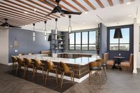 Sophisticated communal kitchen with chic bar seating, modern pendant lights, and a panoramic window view.