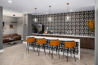 Chic apartment lounge with stylish bar seating, modern lighting, and a bold geometric backsplash.