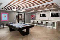 Chic recreation room with a sleek pool table, modern seating, and stylish ceiling lights, perfect for entertaining.