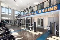 Bright and modern fitness center with floor-to-ceiling windows, state-of-the-art exercise equipment, and motivating signage.