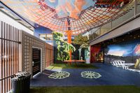 Vibrant communal space with colorful murals, featuring artistic ceiling designs and a blend of open seating, creating a lively and engaging atmosphere.
