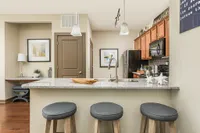 Modern kitchen with granite countertop, sleek bar stools, and stylish wood cabinetry, offering a perfect blend of functionality and elegance.