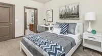 Inviting bedroom with modern decor featuring cozy bedding, stylish desk, and serene artwork.