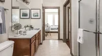Elegant bathroom with chic decor, leading to a cozy bedroom with abundant natural light, highlighting modern apartment living.