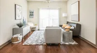 Inviting living room with modern decor, featuring a cozy gray sofa, stylish chairs, and elegant wooden flooring.