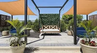 Luxurious outdoor patio with modern swing, vibrant greenery, and stylish sun shades, perfect for relaxation.