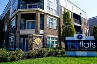 Modern apartment complex exterior with elegant brickwork and lush landscaping at The Flats at Fishers Marketplace.
