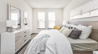 Bright and inviting bedroom with a cozy bed, elegant dresser, and stylish decor, perfect for relaxation.