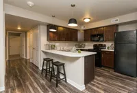 Modern cherry cabinets, a functional breakfast bar, and a seamless layout create a warm and welcoming kitchen space.
