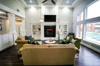 Kick back and connect in the bright and inviting resident lounge at The Bristol, featuring cozy seating, a fireplace, and views of the outdoor pool.