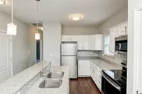 A sleek kitchen designed for everyday living—granite countertops, a glass-top stove, stainless steel appliances, and a kitchen island that doubles as a breakfast bar.