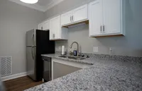 Modern kitchen with sleek stainless steel appliances, elegant white cabinets, and granite countertops, perfect for culinary creativity.