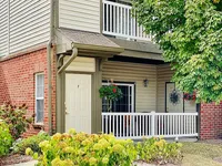 Charming apartment exterior with a cozy private porch, lush greenery, and vibrant flowers.