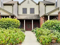Charming townhouse entrance with classic brick facade and lush green landscaping.
