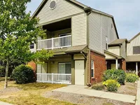 Charming two-story apartment exterior featuring welcoming balconies and lush landscaping.