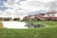 Charming apartment complex with picturesque lakeside views, surrounded by lush greenery and vibrant autumn foliage.