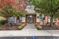 Gateway Crossing Leasing Center with inviting brick facade, lush landscaping, and charming rocking chairs.