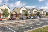 Charming suburban apartment complex with modern two-story buildings, ample parking, and scenic landscaping.