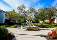 Mature trees, winding sidewalks, and a calming fountain create a courtyard that feels like a hidden garden — right in the heart of Carmel.