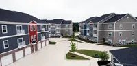 A bird’s-eye view of home: The Ventry’s quiet community layout offers space to breathe, stroll, and settle in. Charming apartment complex with colorful facades, lush green spaces, and modern balconies offering a serene living environment.