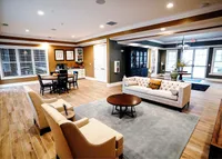 Whether you’re working remote or catching up with neighbors, the clubhouse makes it easy to stay connected and comfortable. Elegant living room showcasing modern design with a plush sofa, stylish armchairs, and a cozy dining area, bathed in natural light.