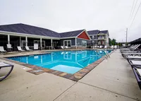 Sun, shade, and plenty of space to unwind. Our sundeck is made for slow mornings and long afternoons. Inviting apartment complex with a modern outdoor pool area, surrounded by comfortable lounge chairs and lush greenery.