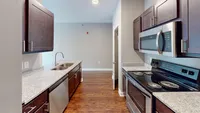Everything in its place, including stainless appliances, a full pantry, double sink, and built-in dishwasher to make cleanup a breeze. Modern kitchen with sleek granite countertops, stainless steel appliances, and dark wood cabinetry creating an elegant cooking space.