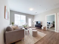 Spacious and light-filled with plenty of room to make it feel like home. Bright and inviting living room with plush sofa, stylish decor, and adjoining bedroom in a modern apartment.
