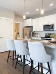 An open kitchen with modern appliances and a breakfast bar that’s both functional and stylish. Chic, modern kitchen with sleek white cabinets, stainless steel appliances, and a stylish breakfast bar seating three.