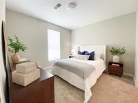 A calm, comfortable bedroom with space to unplug and recharge. Inviting bedroom featuring a cozy bed with plush pillows, warm natural lighting, and stylish decor accentuated by vibrant green plants.