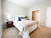 Your space flows easily from bedroom to closet to bath, keeping mornings calm and simple. Inviting bedroom with plush carpeting, elegant bed, cozy side lamp, and walk-in closet for a touch of luxury.